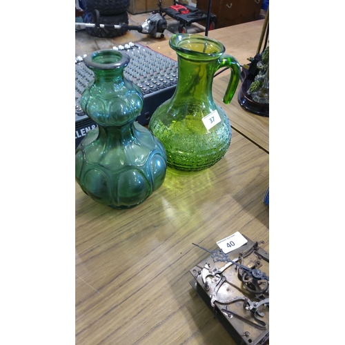 37 - Two vintage green glass pitchers, one with an embossed floral pattern and one with a bulbous paneled... 