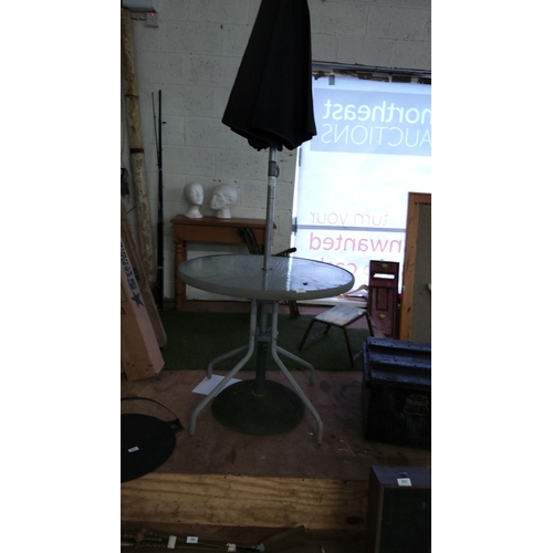 377 - Outdoor glass-top patio table with metal frame, accompanied by a black patio umbrella.