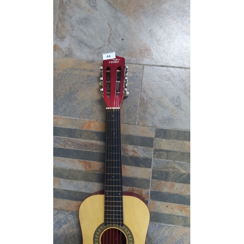 44 - CB Sky acoustic guitar with a classic wooden body and decorative rosette. It has a red headstock, ny... 