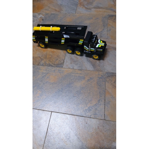 133 - Large vintage toy transport truck with bold black, yellow, and green design. It has six wheels, a ro... 