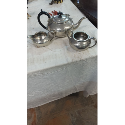 177 - Silver-plated three-piece tea set, featuring a teapot, sugar bowl, and creamer with a black curved h... 