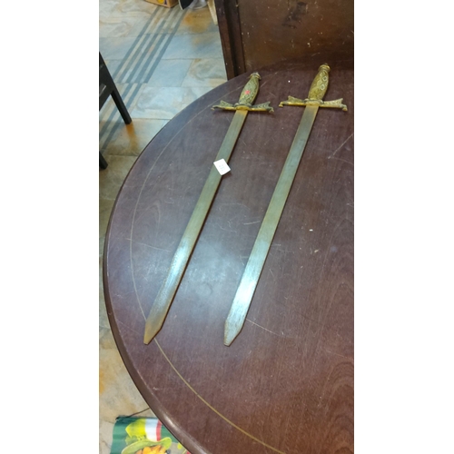 231 - Pair of vintage decorative swords with brass hilt and ornate detailing. Straight, double-edged blade... 