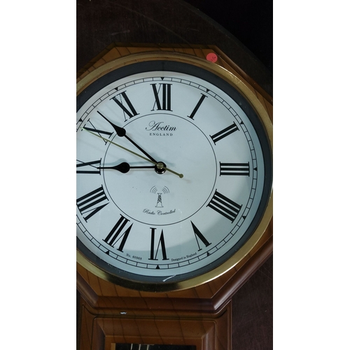 234 - Acctim England radio-controlled wall clock with pendulum features a classic wooden case with Roman n... 