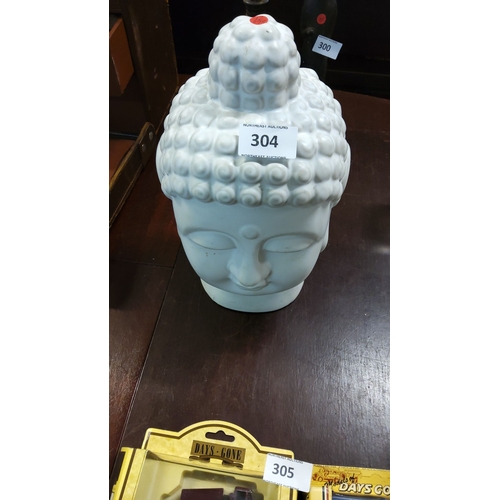 304 - White ceramic Buddha head sculpture features a serene expression and textured hair bun with a smooth... 