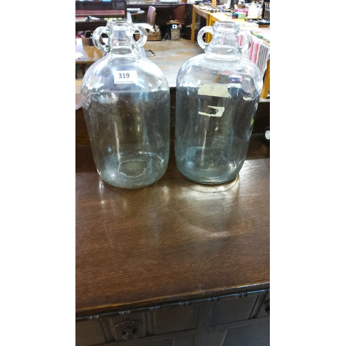 319 - Pair of vintage clear glass demijohn bottles with double-loop handles.