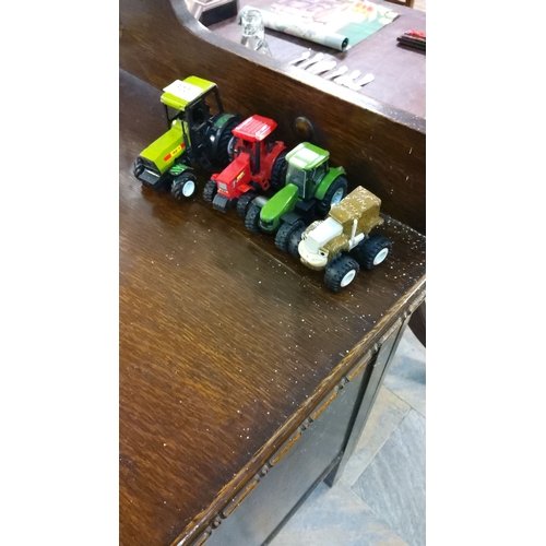 320 - Set of four toy tractors in various colors and designs. The toys have rugged wheels.