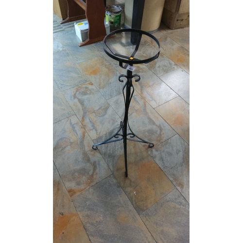 411 - Black wrought iron plant stand with decorative scrollwork features a sturdy tripod base and a circul... 