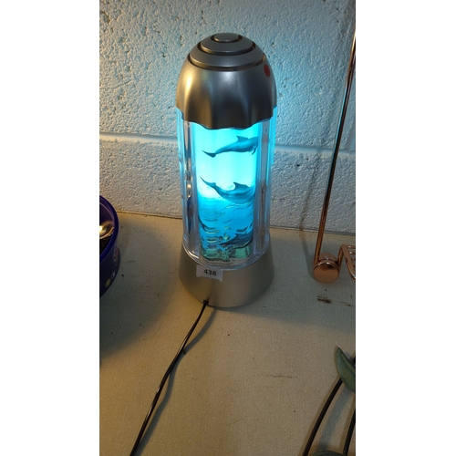 438 - Modern dolphin motion lamp features an illuminated water effect and a cylindrical design with a meta... 