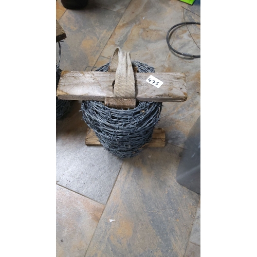 475 - Roll of barbed wire with wooden support and carrying strap.