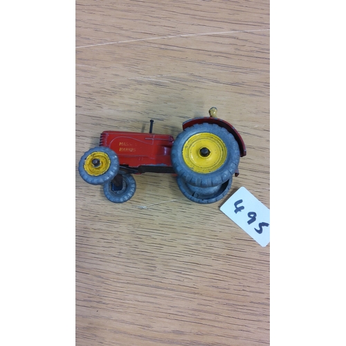 495 - Vintage Massey Harris diecast toy tractor with driver, featuring a red body, yellow wheels, and rubb... 