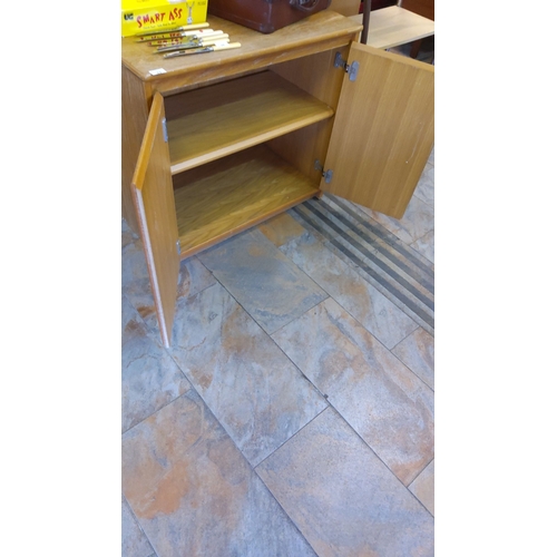 73 - Mid-century oak storage cabinet with double doors and interior shelving, featuring a natural wood gr... 