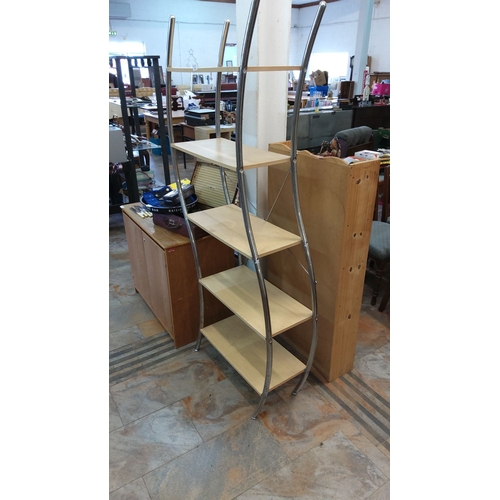 79 - Modern curved metal and wood shelving unit with five light wood shelves supported by a sleek chrome-... 