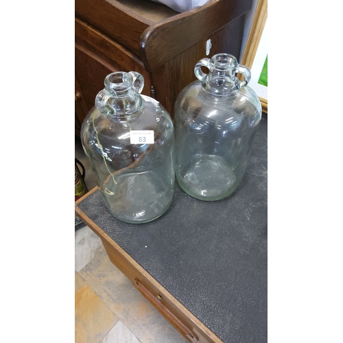 83 - Pair of vintage clear glass demijohn bottles with applied loop handles. Classic utilitarian design.