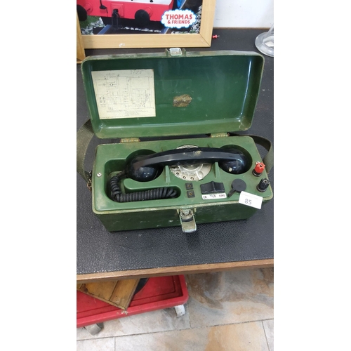 85 - Vintage military field telephone in green metal case, featuring rotary dial, handset, and original s... 