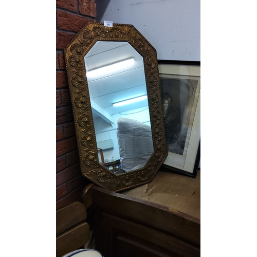 79 - Early 20th-century octagonal wall mirror with an embossed gilt-metal frame featuring floral motifs.