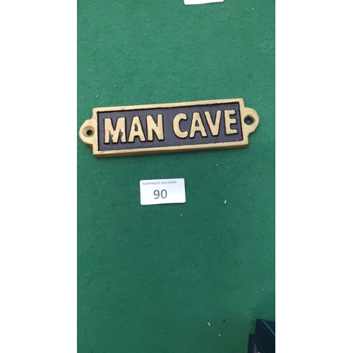 90 - Small rectangular metal wall plaque with raised gilt lettering reading “MAN CAVE” on a black recesse... 