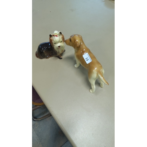 13 - Pair of glazed porcelain dog figurines: a seated Yorkshire terrier with red bow and a standing golde... 