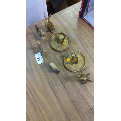 35 - Group of cast brass animal miniatures, comprising two ring trays with feline finials, seated hares, ... 