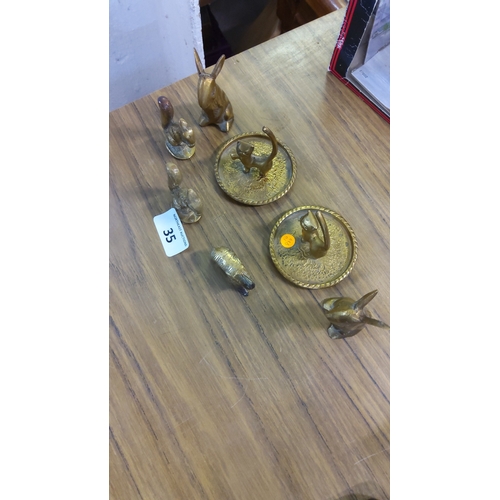 35 - Group of cast brass animal miniatures, comprising two ring trays with feline finials, seated hares, ... 