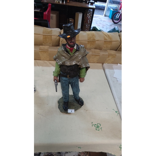 5 - Painted resin figure of poncho-clad cowboy with revolver and black hat, standing on rocky base, late... 