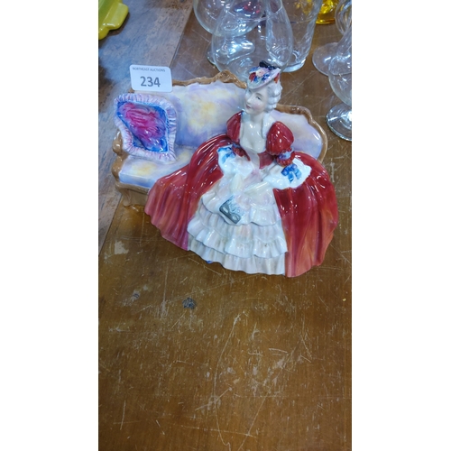 234 - Hand-painted bone china Royal Doulton  figurine, ‘Belle O’ The Ball’, lady in crimson gown seated on... 