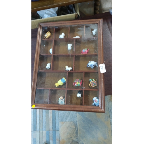 235 - Glazed wooden compartmented display cabinet housing assorted miniature ceramic figures, including se... 