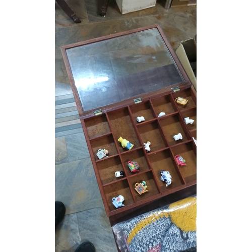 235 - Glazed wooden compartmented display cabinet housing assorted miniature ceramic figures, including se... 