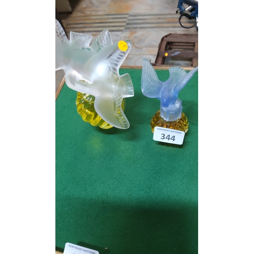 344 - Pair of amber glass perfume bottles with moulded frosted glass bird stoppers—one clear dove, one pal... 