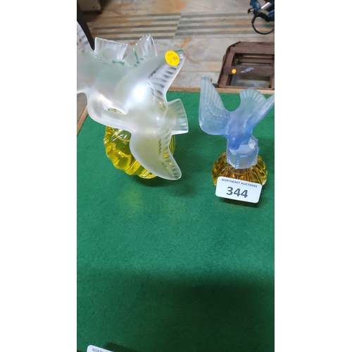 344 - Pair of amber glass perfume bottles with moulded frosted glass bird stoppers—one clear dove, one pal... 