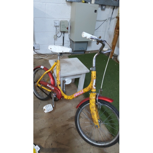 396 - Yellow and red Raleigh “Rascal” children’s single-speed bicycle with small wheels, white saddle and ... 