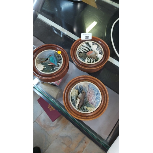 38 - Set of three small turned wood circular reliefs,inset with hand-painted ceramic bas-relief panels de... 