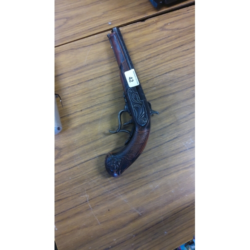 42 - A decorative flintlock-style pistol-shaped wall plaque, of brown moulded resin with blackened relief... 