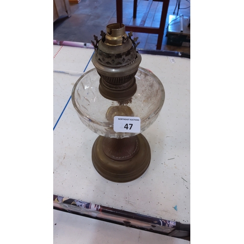 47 - A glass oil lamp font on circular brass-effect base, fitted a brass burner with pierced gallery and ... 