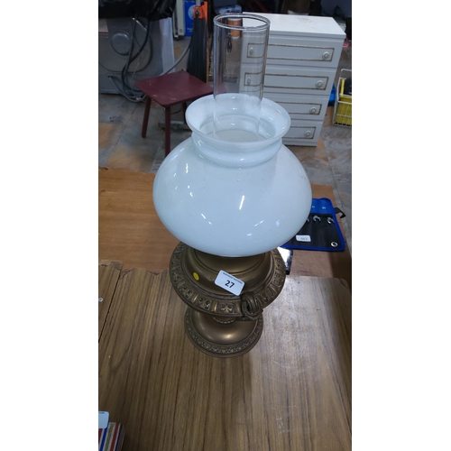 27 - An oil lamp, with clear glass chimney and white opaline glass globe shade, set on a cast metal base ... 