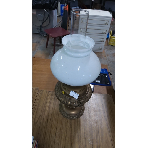 27 - An oil lamp, with clear glass chimney and white opaline glass globe shade, set on a cast metal base ... 