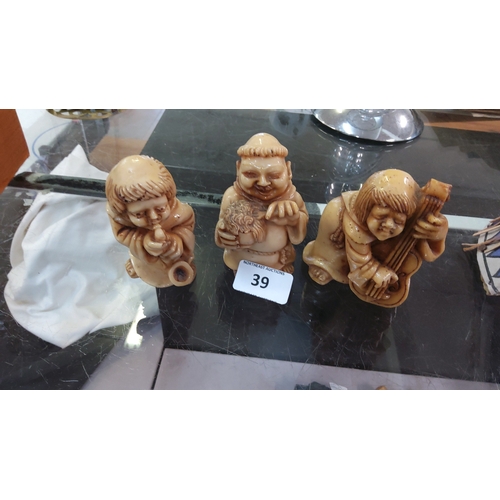 39 - Set of 3 carved Japanese-style netsuke figures in ivory-tone material, depicting a kneeling musician... 