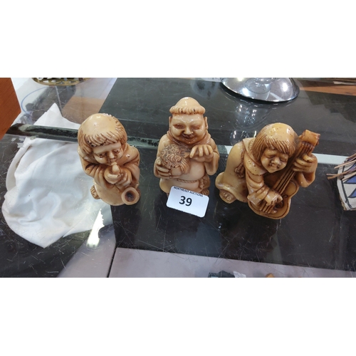 39 - Set of 3 carved Japanese-style netsuke figures in ivory-tone material, depicting a kneeling musician... 