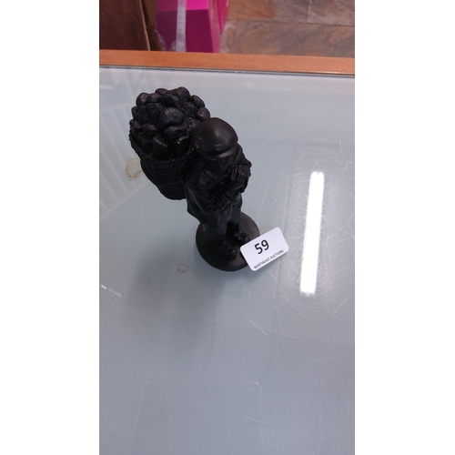 59 - A cast resin figure modelled as an Irish turf cutter carrying a creel of turf on his back, on a circ... 