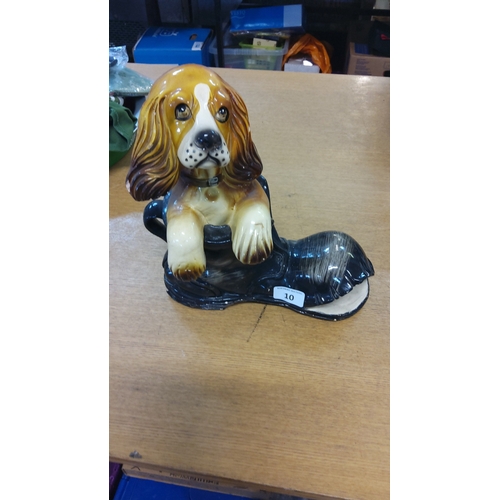10 - Glazed earthenware model of a spaniel resting its forepaws on a black boot, naturalistically painted... 