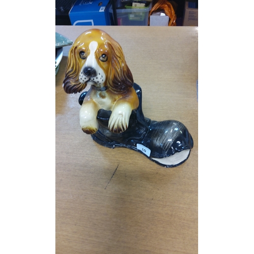 10 - Glazed earthenware model of a spaniel resting its forepaws on a black boot, naturalistically painted... 