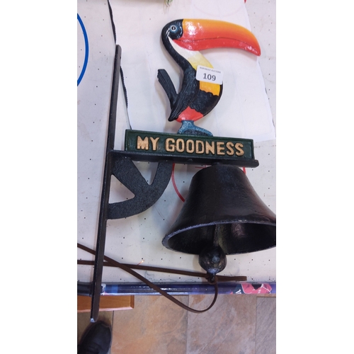 109 - Cast-iron wall-mounted bell bracketed with a polychrome toucan finial above a raised-letter plaque r... 