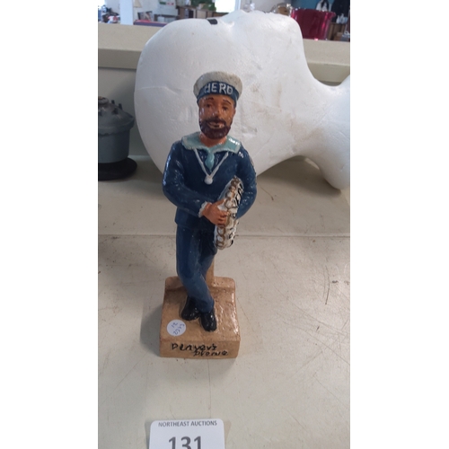 131 - Folk-art painted resin figure of a sailor in blue uniform and cap, holding a scroll inscribed “Playe... 