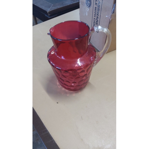 4 - Cranberry glass jug of baluster form, the lower body moulded with a repeating honeycomb motif, with ... 