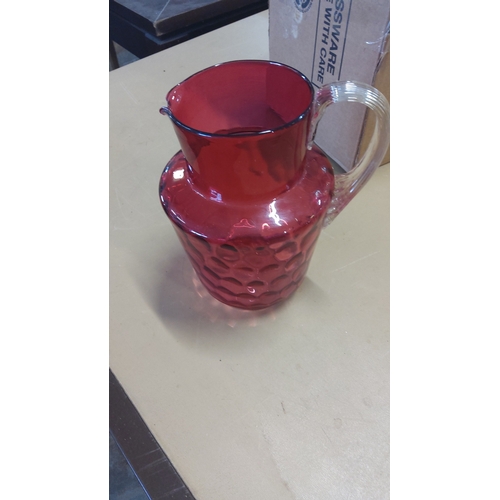 4 - Cranberry glass jug of baluster form, the lower body moulded with a repeating honeycomb motif, with ... 