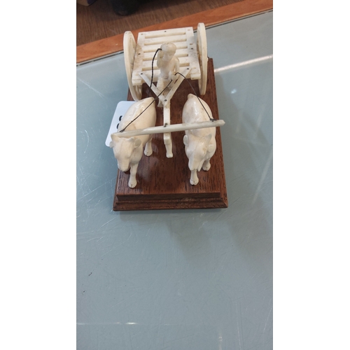 53 - Carved ivory tone model of an ox-drawn cart with standing driver, the slatted two-wheeled vehicle ha... 