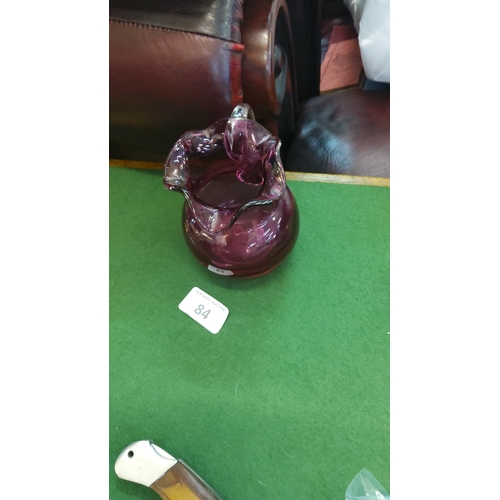 84 - Art cranberry glass jug , of globular form with a flared, crimped rim and an applied clear glass loo... 