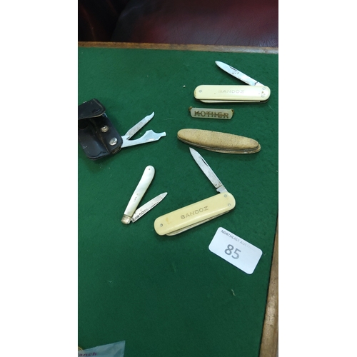 85 - A small group of pocket knives, including two Sandoz promotional penknives with cream plastic scales... 