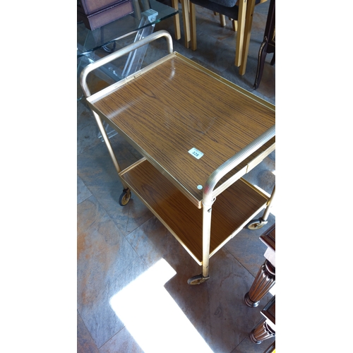 328 - Mid-20th century two-tier tea trolley with faux wood-grain laminate trays within a gilt-metal tubula... 