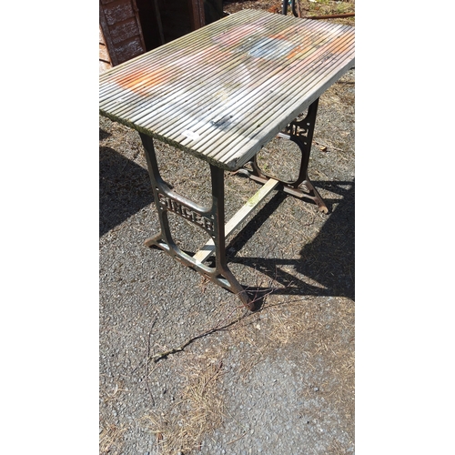 488 - Industrial work table with cast-iron trestle ends pierced with the word ‘SINGER’, joined by wooden s... 