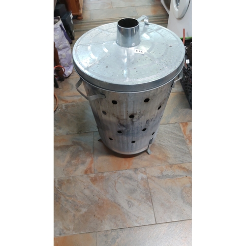 526 - Galvanised metal incinerator bin with domed lid and central flue, the cylindrical body pierced with ... 